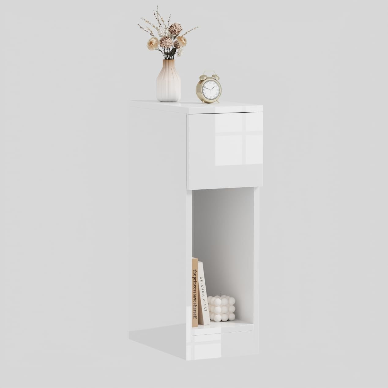 Modern Home narrow white bedside table with a top drawer and open storage shelf, styled with a vase and alarm clock.