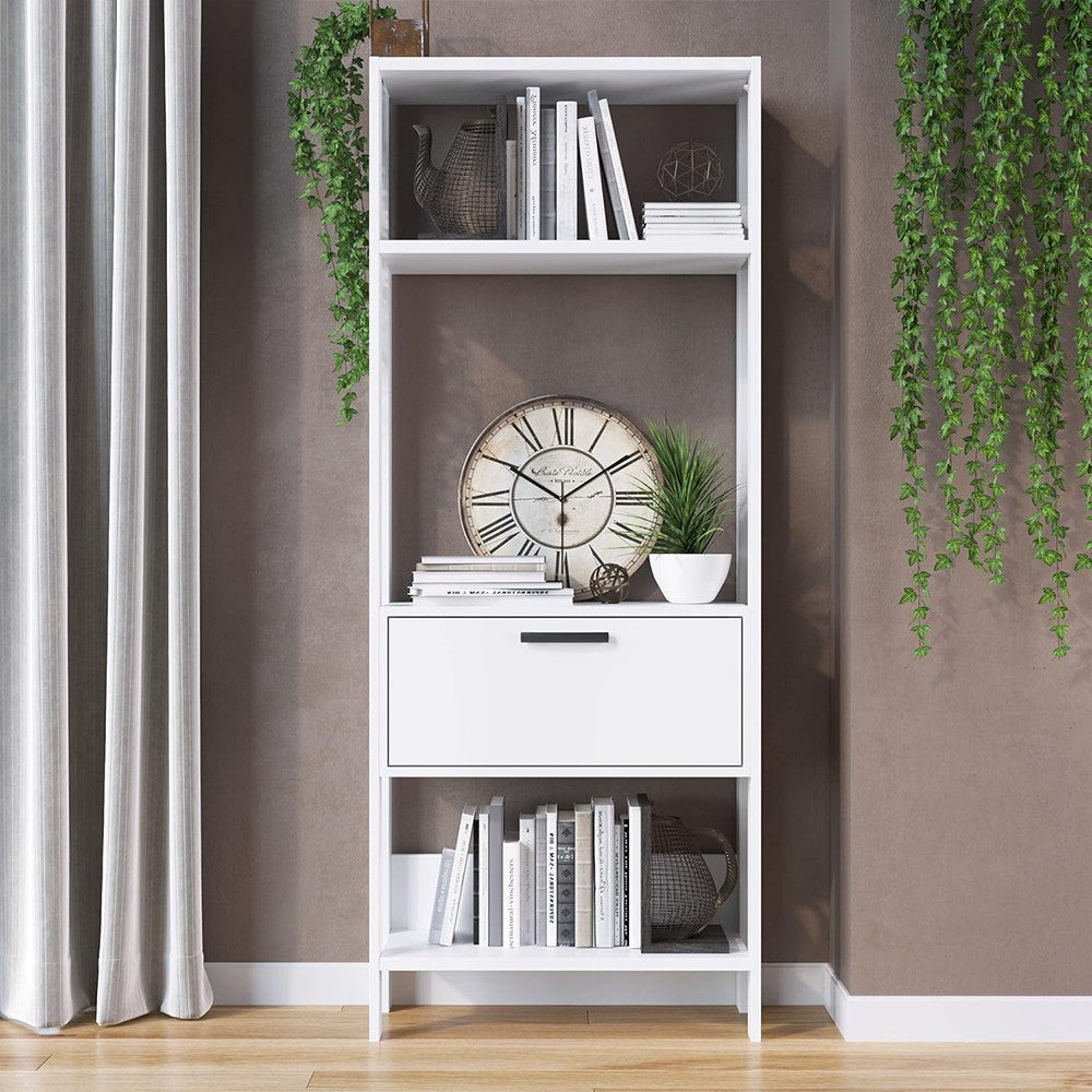 Modern Home tall white bookshelf with open shelves and a central storage drawer, styled with books and decor.