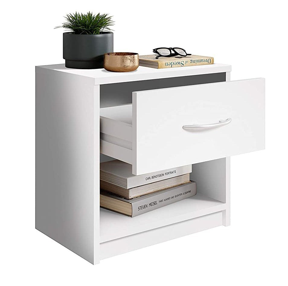 Modern Home white bedside table with an open drawer, storage shelf, and aluminum handle, styled with books and plant.