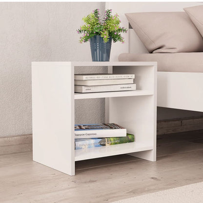 Modern Home white bedside table with two open shelves, holding books and a small potted plant next to a bed.